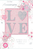 This anniversary card is a gentle tribute to enduring romance, its design as soft and thoughtful as a quiet evening at home in Ilford. At the centre, the word LOVE appears in raised, velvety letters sprinkled with delicate pastel glitter, with the O transformed into a radiant silver heart that catches the light like a small jewel. The texture of the lettering stands out under the fingertips, giving the design depth and a sense of handcrafted care. Encircling this focal point is a drift of painted blossoms in blush, mauve, and creamy ivory, their edges softened into a watercolour-like haze that suggests petals just beginning to unfurl. The flowers and leaves curl and swirl across the card in fluid lines, echoing the graceful shapes of a romantic bouquet arranged for an Ilford anniversary celebration. Tiny flourishes-stray petals, slender swirls, and subtle butterflies-add a hint of movement, as though the flowers were gently shifting in a light breeze along The Drive or near Ilford Hill. The phrases On Our Anniversary and I love you today and always are written in a slim, elegant script, their charcoal-grey ink harmonising with the pastel background instead of dominating it. Soft tones of silvery grey weave through the design, grounding the romantic pinks and giving the card a refined, contemporary feel. Altogether, the piece feels like a whispered promise captured on paper, perfectly suited to accompany a fresh bouquet delivered across Ilford, and to mark another chapter in a shared love story.